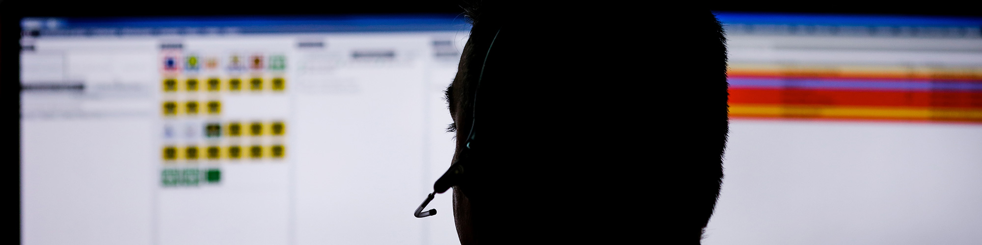 silhouette of a crisis response line operator wearing a headset, sitting at a computer