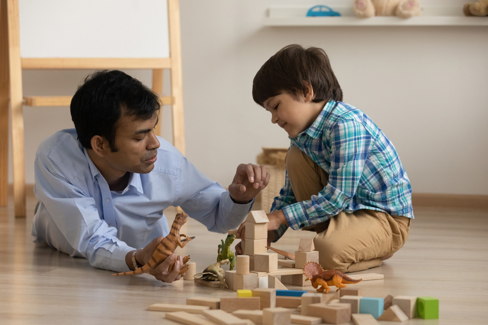 a father and son playing with blocks on the floor