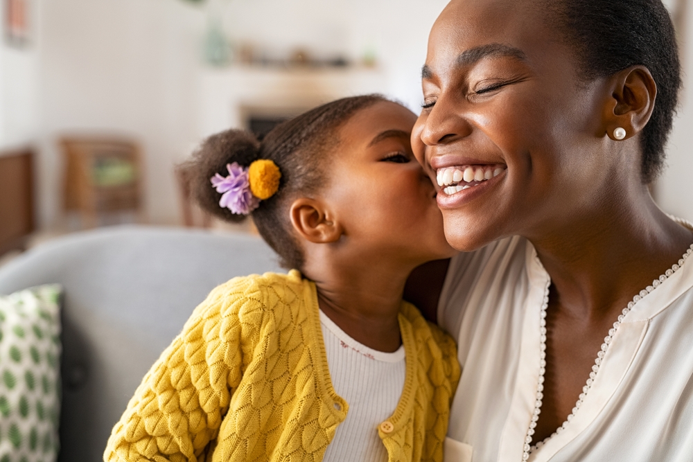  African American child kissing her smiling Mom