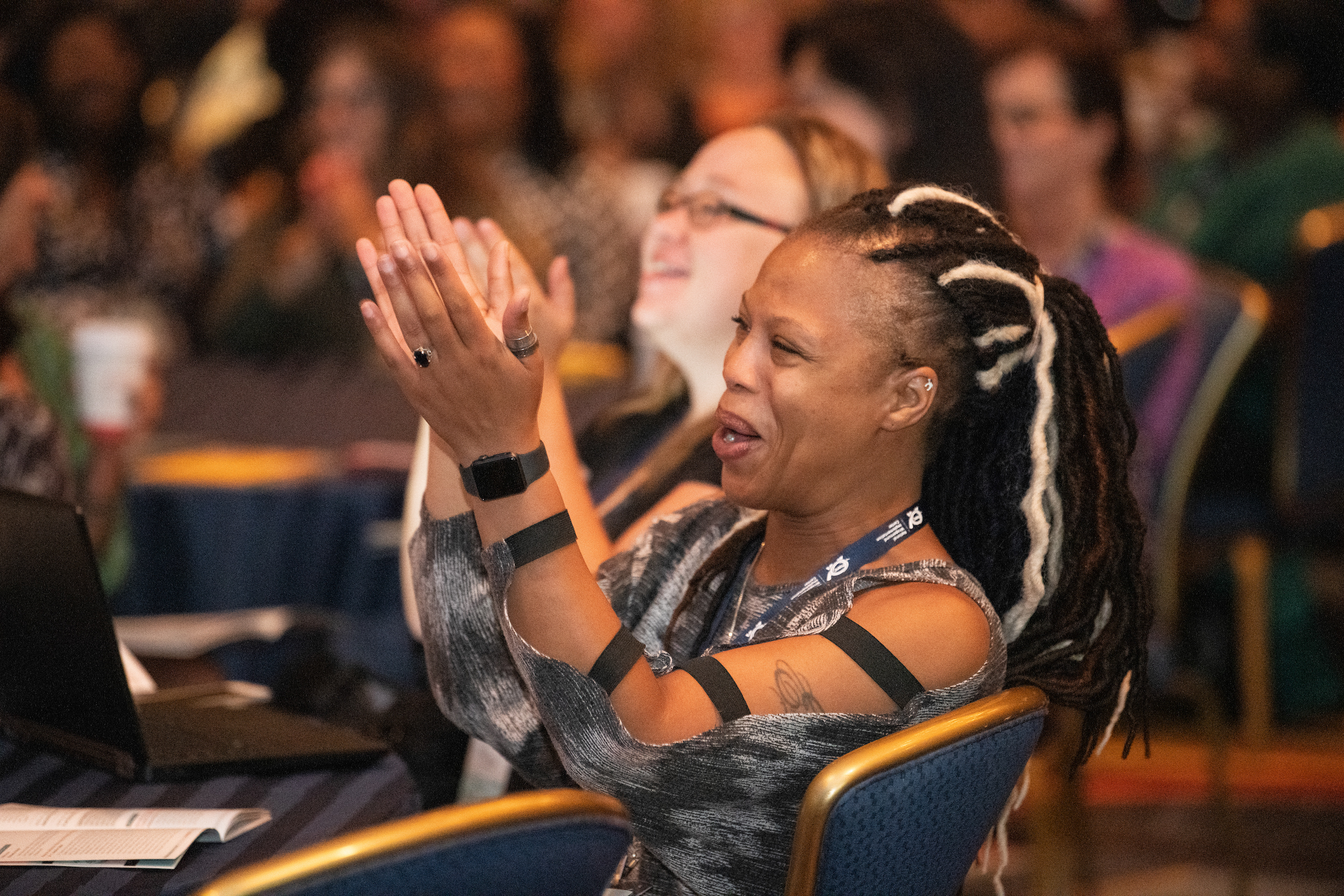 a woman smiling and applauding sitting at a conference