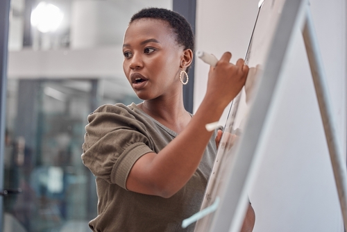 African American woman writing on whiteboard and leading a discussion