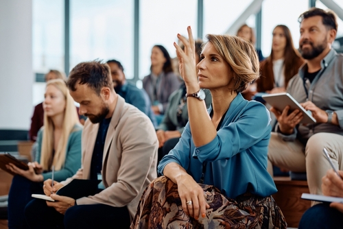 Conference session with woman raising her hand