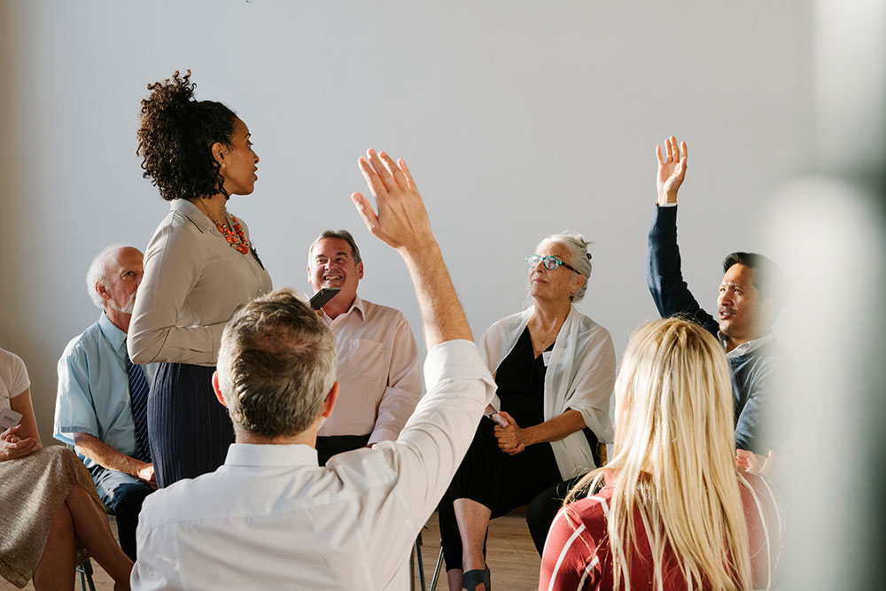 A circle of participants, hands raised, demonstrating enthusiasm and collaboration in a group setting.