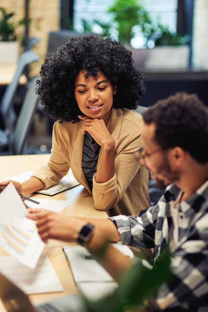 Two,Young,Diverse,Coworkers,Analyzing,Sales,Report,While,Working,Together